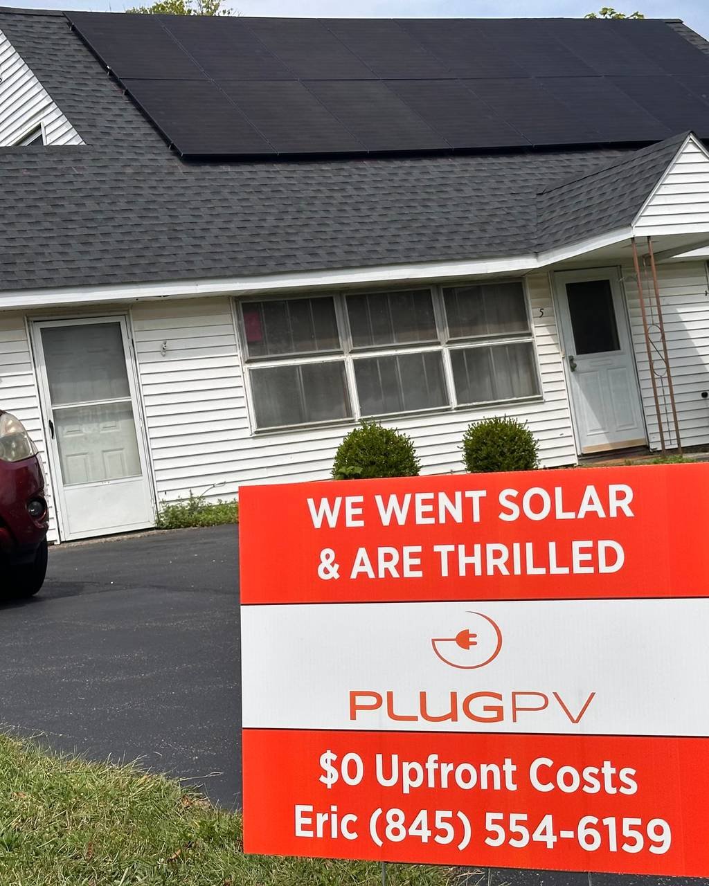 PlugPV yard sign reading "We went solar and are thrilled" with Eric's phone number