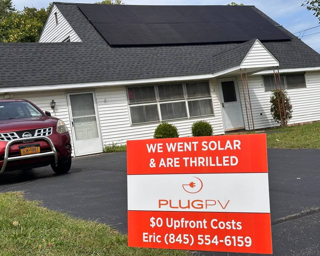 PlugPV yard sign reading "We went solar and are thrilled" with Eric's phone number