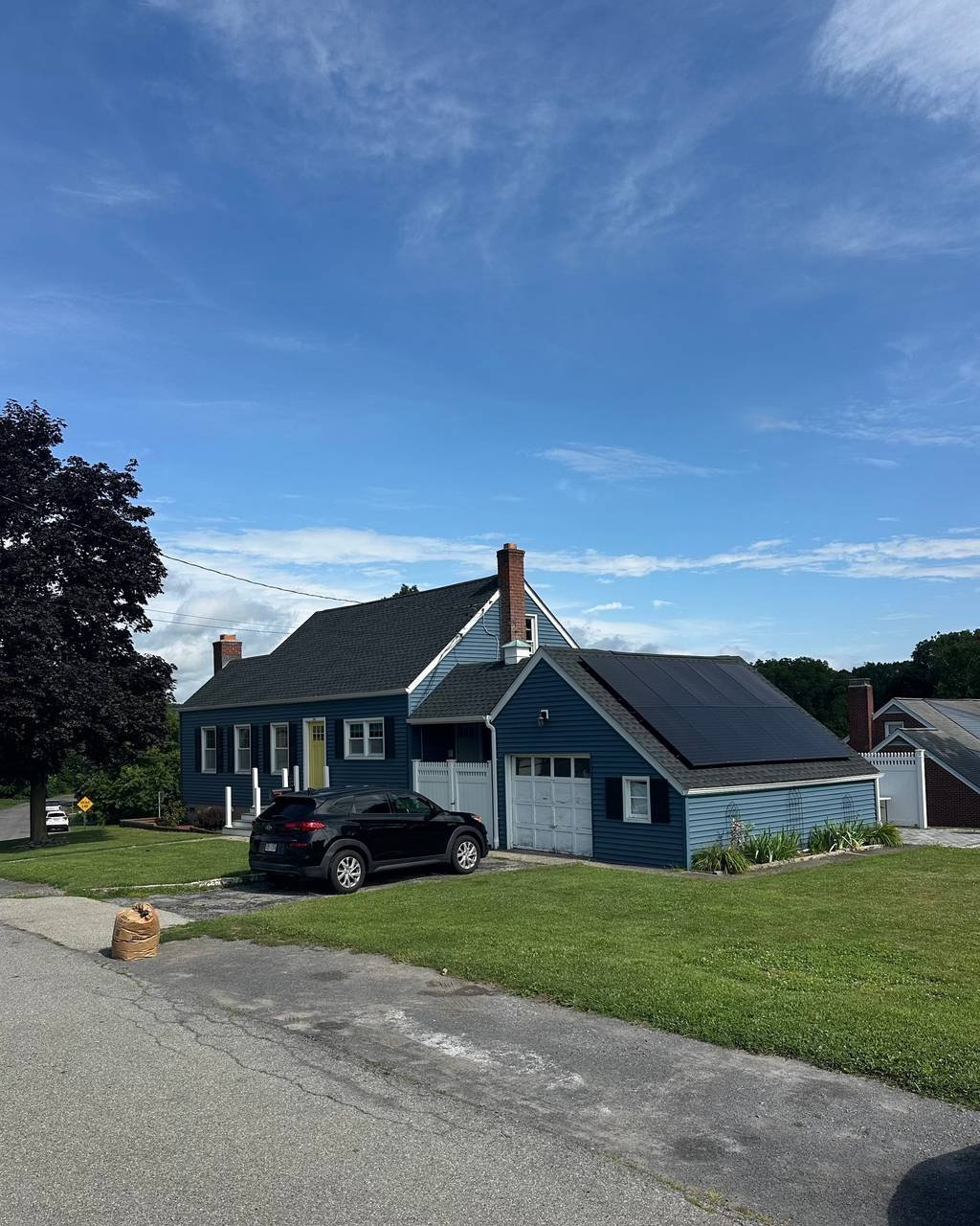 Blue cape-style home with solar panels on the roof
