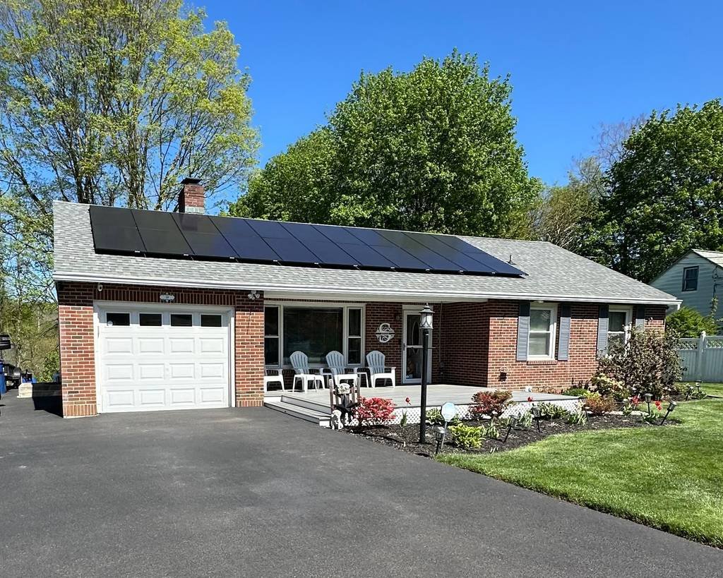 Solar array across the roof of a brick ranch home with a two-car garage
