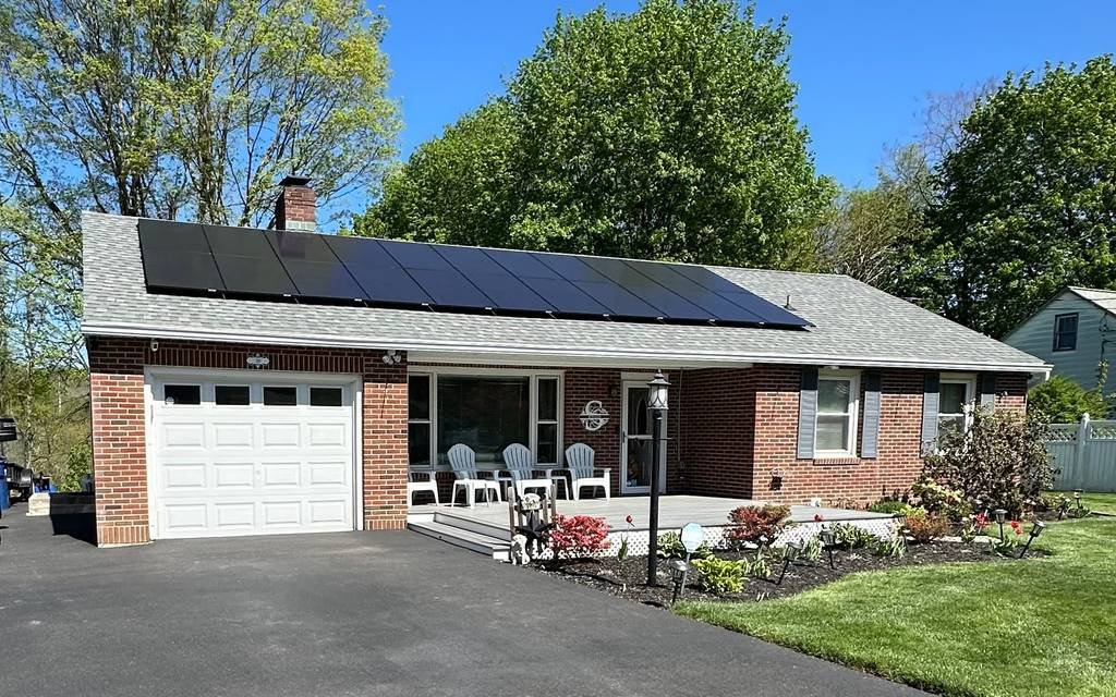 Solar array across the roof of a brick ranch home with a two-car garage