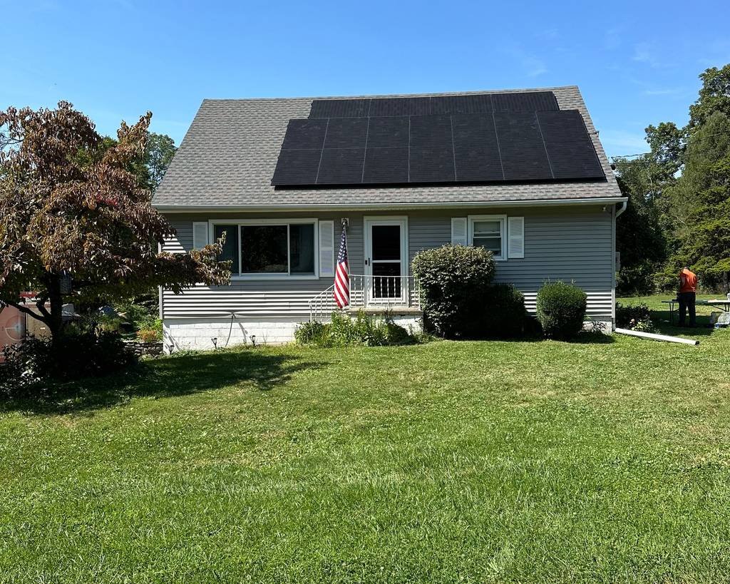 Cape Cod style home with a full roof of black solar panels