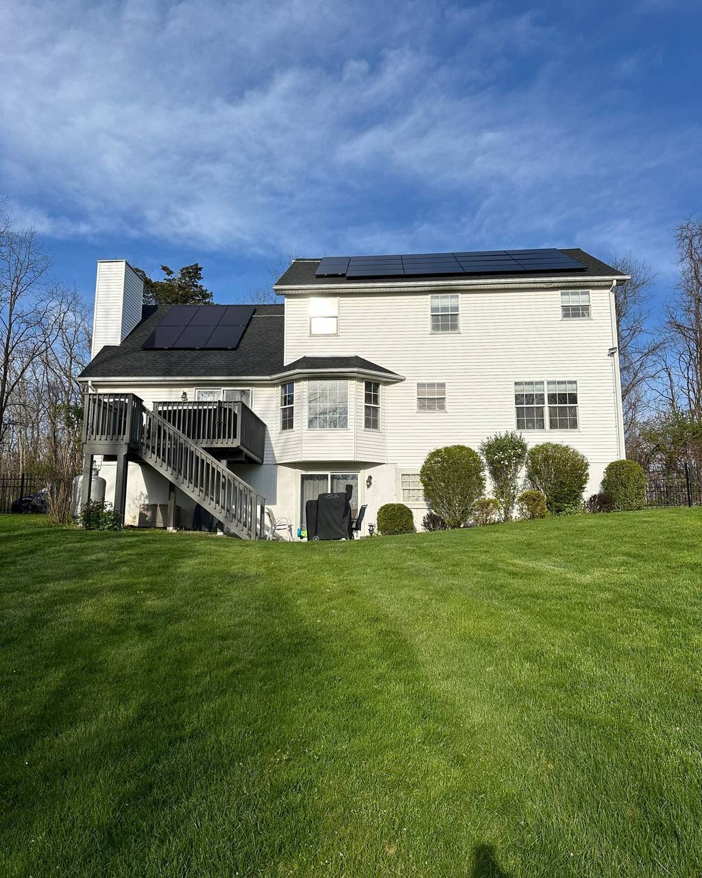 Rear view of a white colonial with solar panels on the upper roof