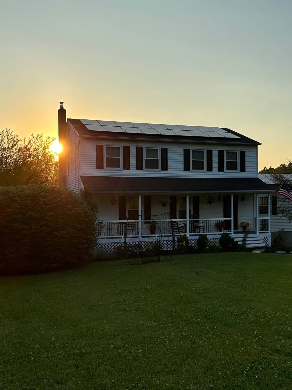 Solar panels across the roof of a two-story colonial home at sunset in the Hudson Valley