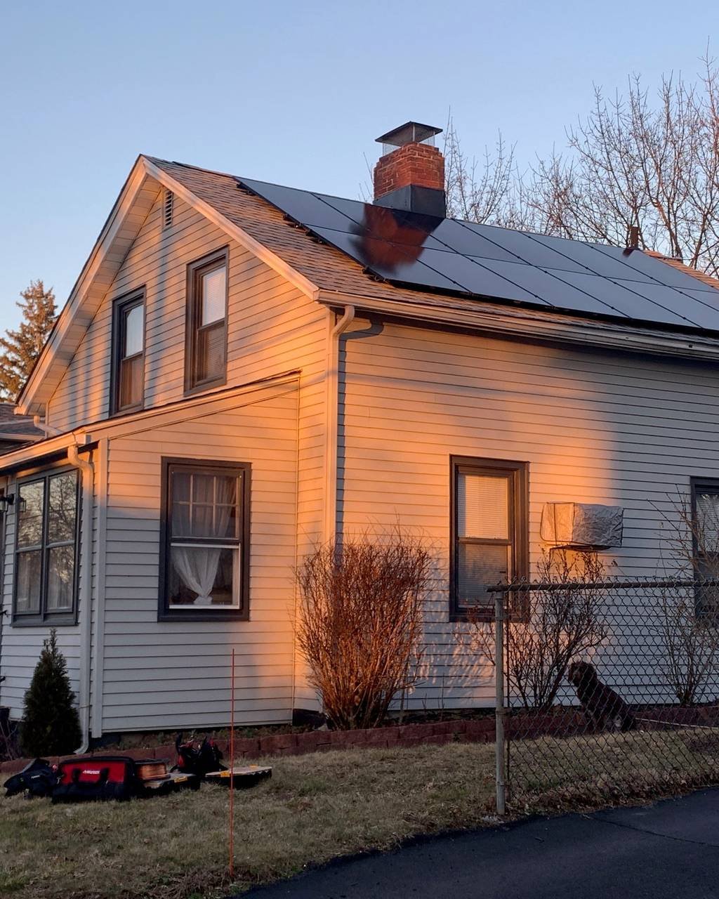 Black solar panels on a farmhouse roof lit by evening sun