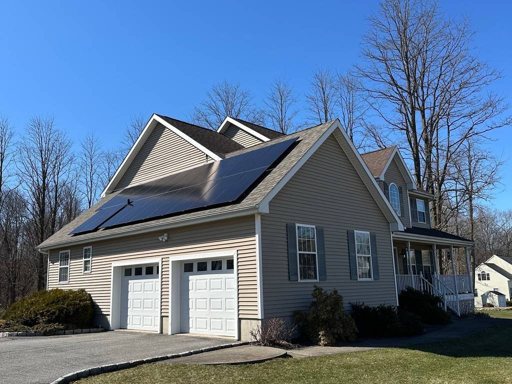 Solar panels on the garage roof of a gray two-story home
