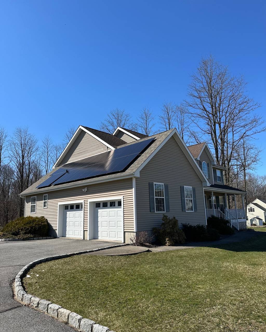 Solar panels on the garage roof of a gray two-story home