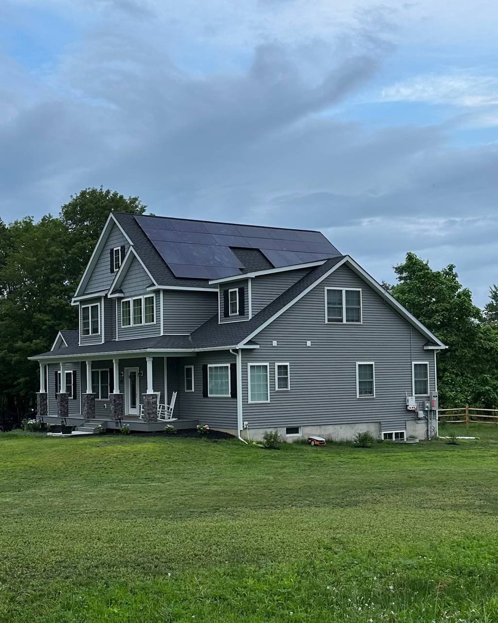 Gray colonial home with solar panels on the side roof