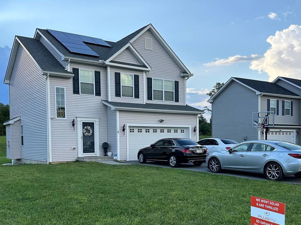 Two-story home with rooftop solar and a PlugPV yard sign on the lawn