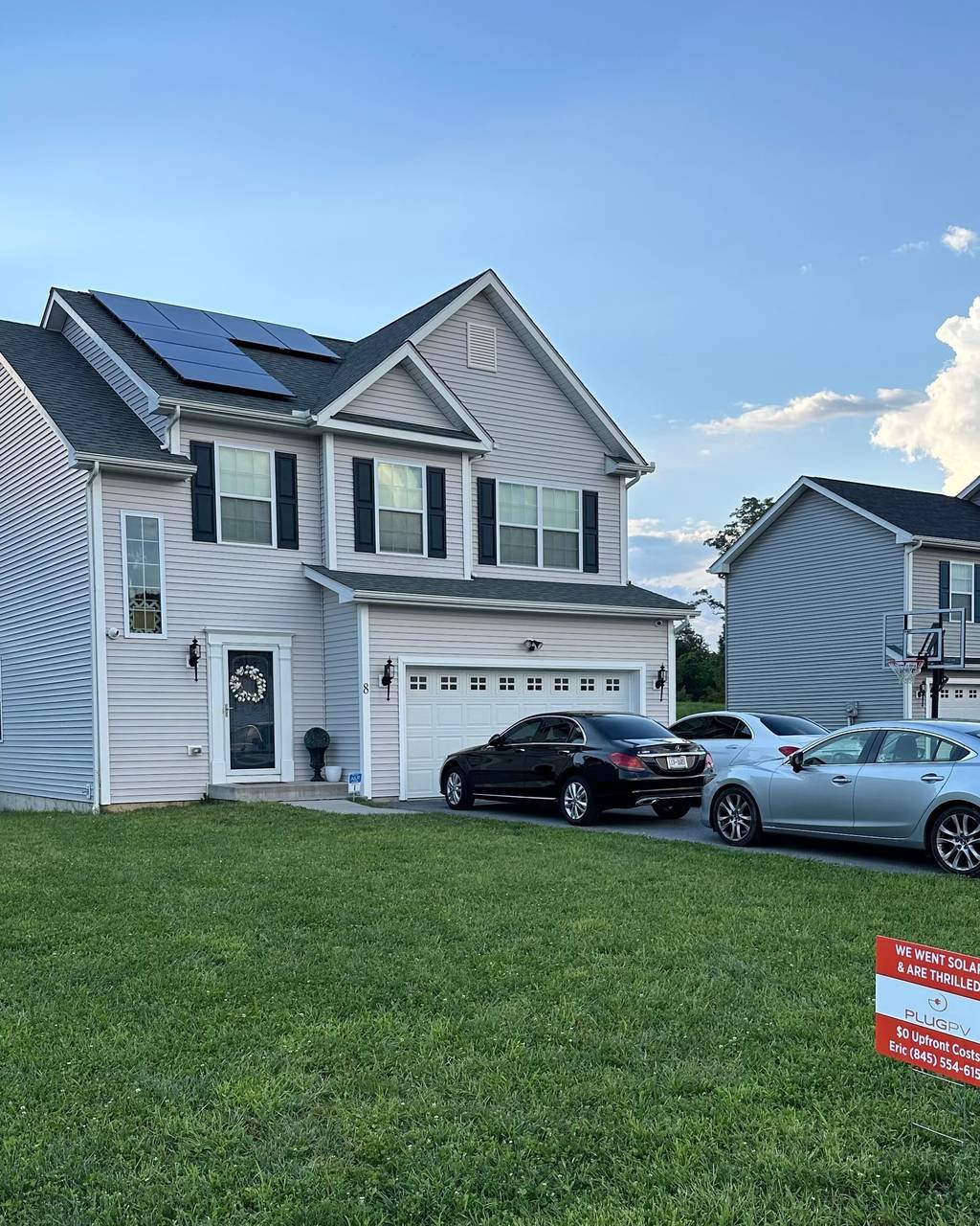Two-story home with rooftop solar and a PlugPV yard sign on the lawn