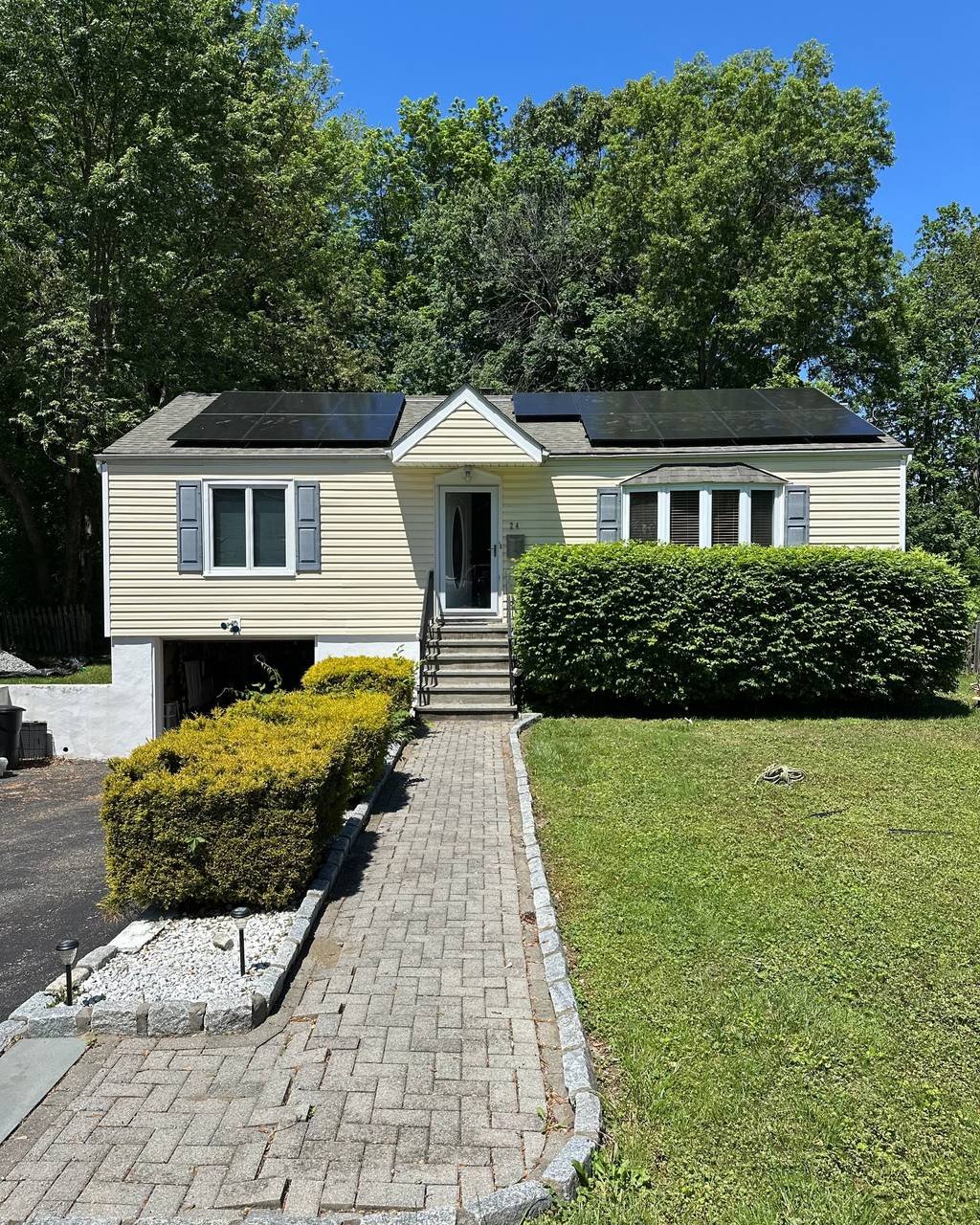 Split-level home with solar panels above a paver walkway